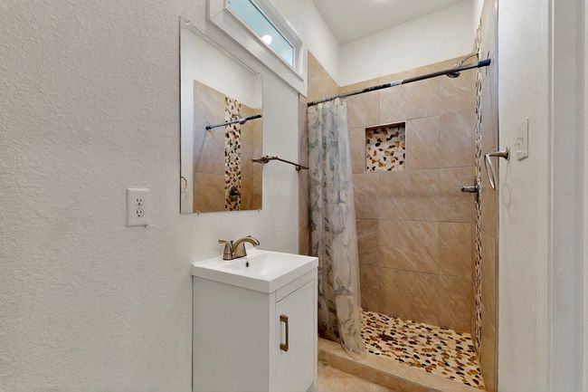 Full bathroom with tiled shower, a textured wall, and vanity | Image 14