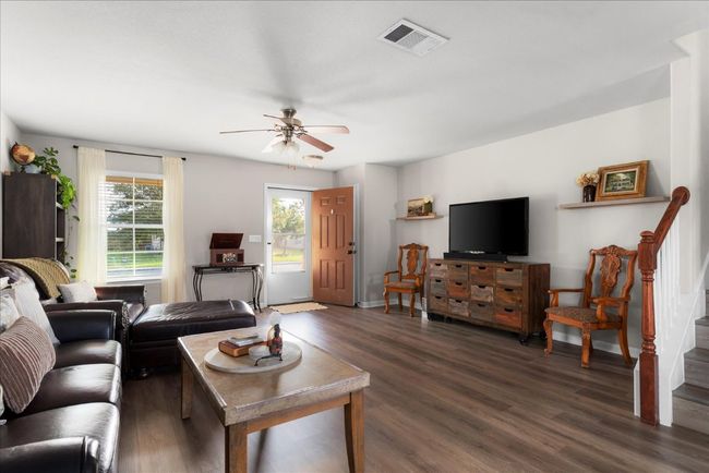 Living room with a ceiling fan, dark wood-style floors, stairs, and baseboards | Image 5
