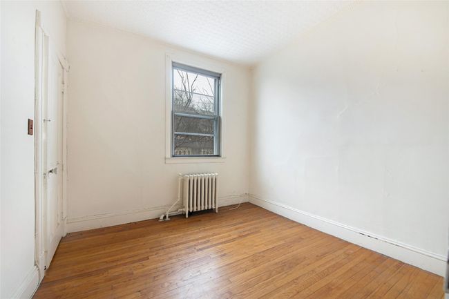 Spare room with a textured ceiling, light wood finished floors, and radiator heating unit | Image 16