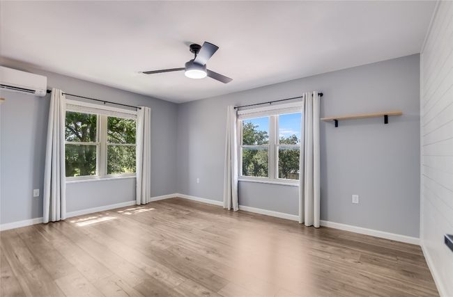 Unfurnished room with healthy amount of natural light, ceiling fan, light wood-style floors, and a wall unit AC | Image 21