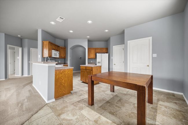 Kitchen with white appliances, arched walkways, light countertops, a peninsula, and brown cabinets | Image 6