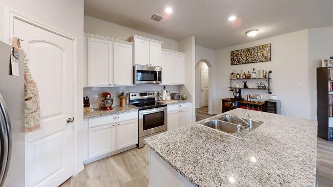 Kitchen with stainless steel appliances, a sink, arched walkways, and light wood finished floors | Image 16