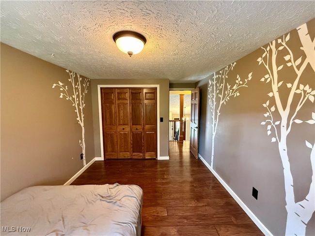 Bedroom with a textured ceiling, a closet, wood finished floors, and baseboards | Image 29
