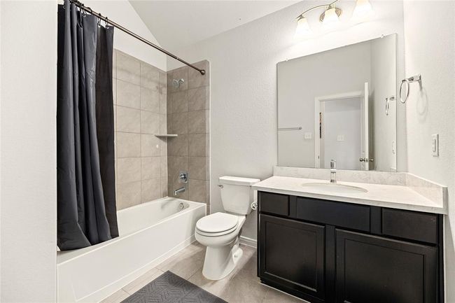 Secondary bathroom features light countertops and cabinets, custom paint, shower/tub combo with tile surround, large mirror, tile floors, sleek fixtures and modern finishes, plenty of space to accommodate any visiting family or guests. | Image 16
