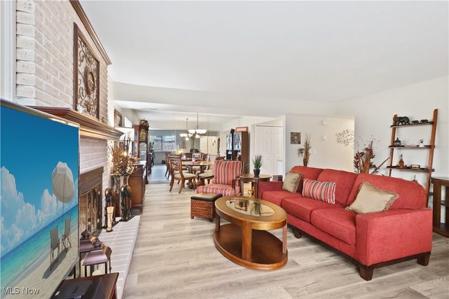 Living room featuring light wood-type flooring, a notable chandelier, and a brick fireplace | Image 10