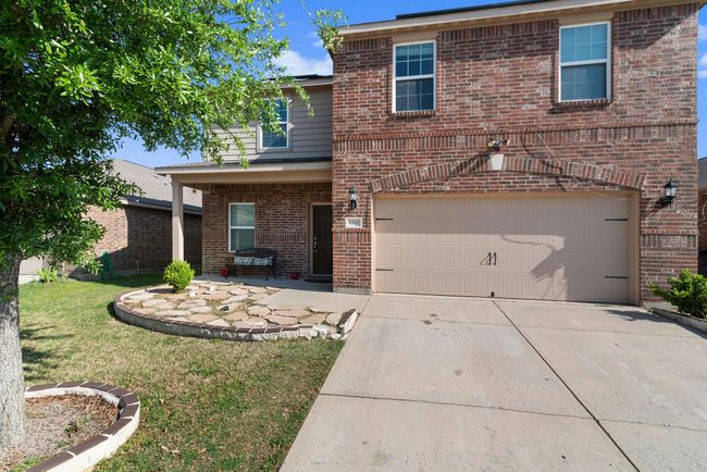Traditional home featuring a front lawn, driveway, brick siding, and a garage | Image 5