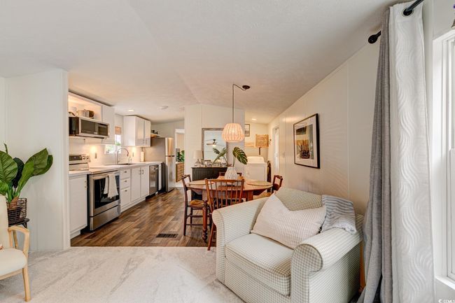 Living area featuring dark wood-type flooring, washer / clothes dryer, and vaulted ceiling | Image 7