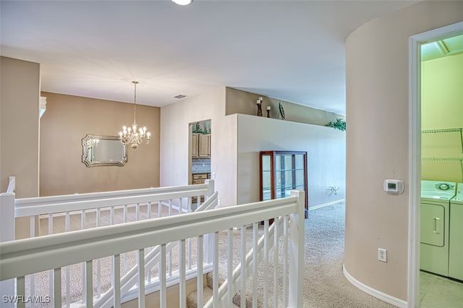 Corridor featuring a chandelier, light carpet, and washer and dryer | Image 11