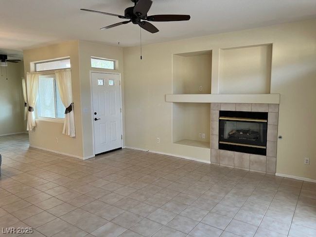 Unfurnished living room featuring a healthy amount of sunlight, baseboards, a fireplace, and a ceiling fan | Image 6