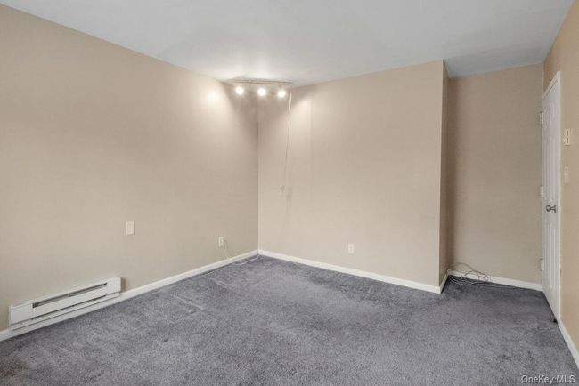 Unfurnished room featuring baseboards, dark colored carpet, and baseboard heating | Image 24
