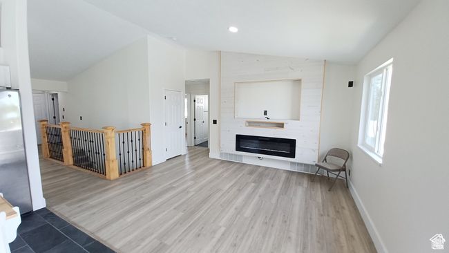 Unfurnished living room featuring vaulted ceiling, wood finished floors, a fireplace, and recessed lighting | Image 11
