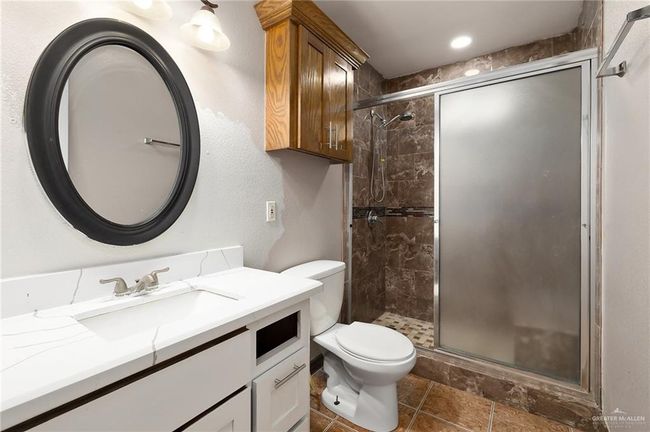 Bathroom featuring a shower with shower door, toilet, and vanity | Image 10