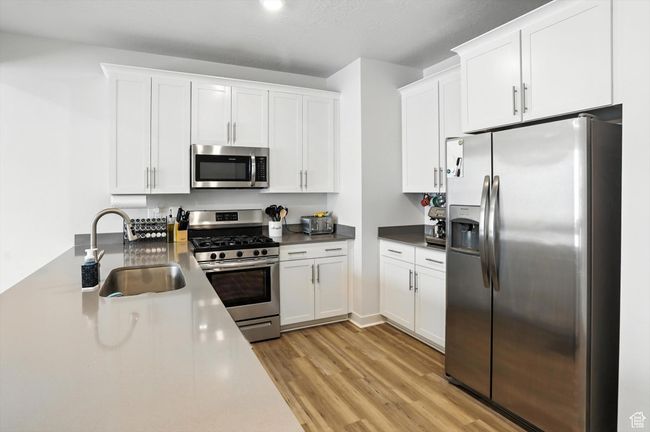 Kitchen with appliances with stainless steel finishes, new light wood-style LVP floors, and white cabinetry | Image 29