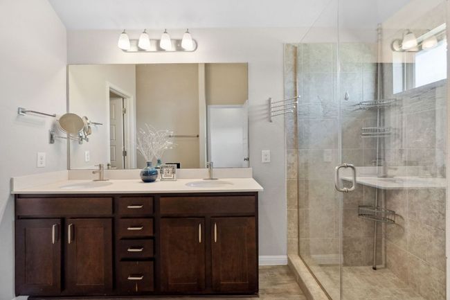 Primary bathroom featuring a dual vanity and a walk-in shower with frameless door | Image 19