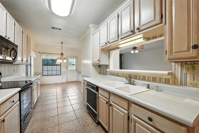 Kitchen featuring black appliances, a textured ceiling, light countertops, ceiling fan, and a chandelier | Image 14