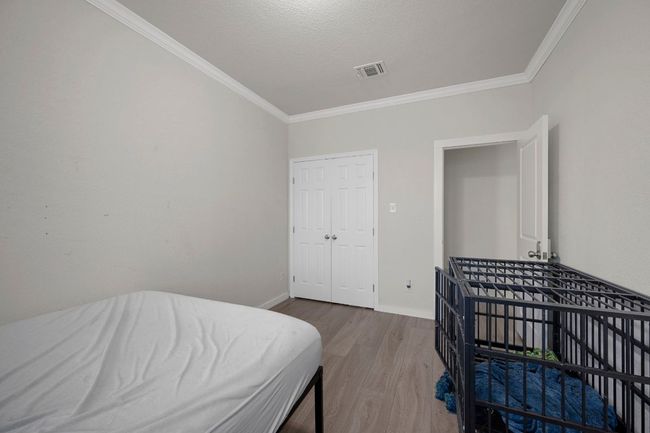 Bedroom featuring baseboards, ornamental molding, visible vents, and wood finished floors | Image 12