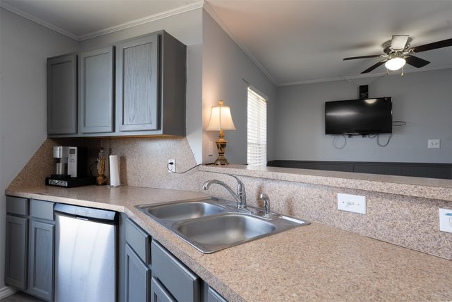 Kitchen featuring dishwasher, a sink, a ceiling fan, crown molding, and tasteful backsplash | Image 12