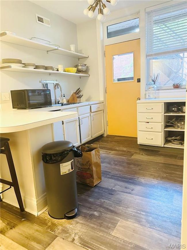 Kitchen featuring white cabinetry, light countertops, dark wood-style flooring, and open shelves | Image 7