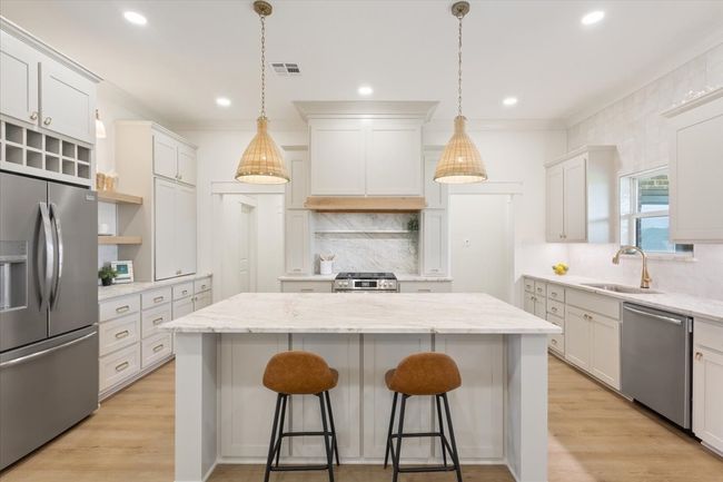 Kitchen featuring appliances with stainless steel finishes, a kitchen island, open shelves, backsplash, and a breakfast bar area | Image 10