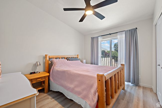 Bedroom featuring light wood-type flooring, vaulted ceiling, access to exterior, and a ceiling fan | Image 15