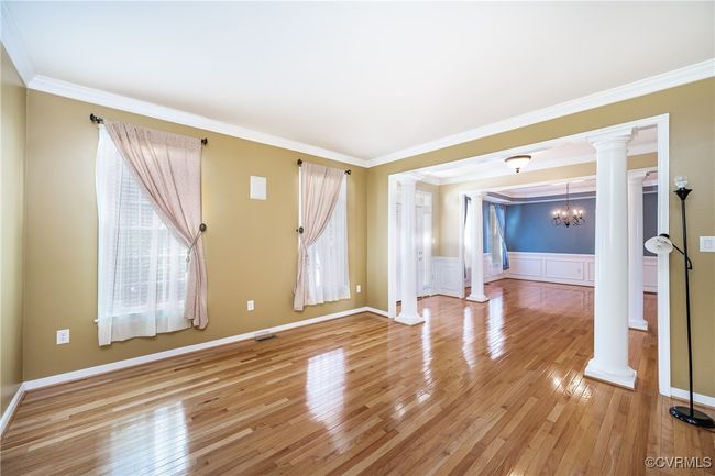 Unfurnished room with ornate columns, light wood-type flooring, plenty of natural light, ornamental molding, and a chandelier | Image 5