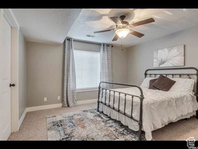 Carpeted bedroom with baseboards, a textured ceiling, and a ceiling fan | Image 7