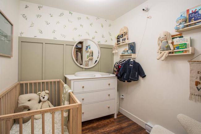 Bedroom with dark wood-style floors, a crib, wallpapered walls, and wainscoting | Image 21