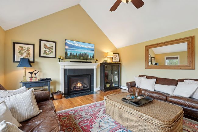 Living area with a fireplace, wood finished floors, a ceiling fan, and high vaulted ceiling | Image 10