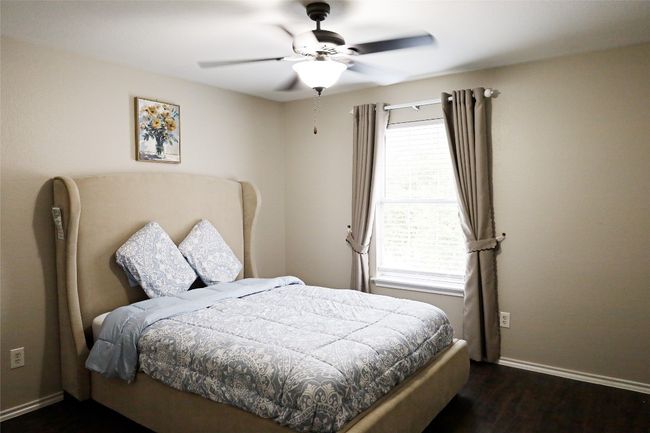 Bedroom with baseboards, ceiling fan, and dark wood finished floors | Image 11