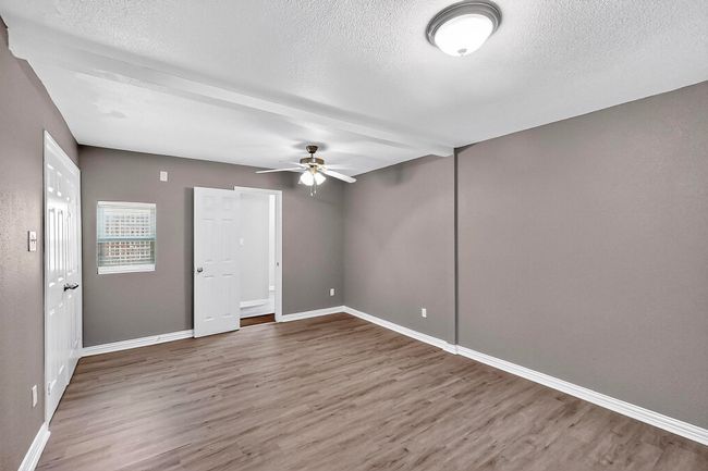 Empty room featuring wood finished floors, a textured ceiling, and a ceiling fan | Image 15