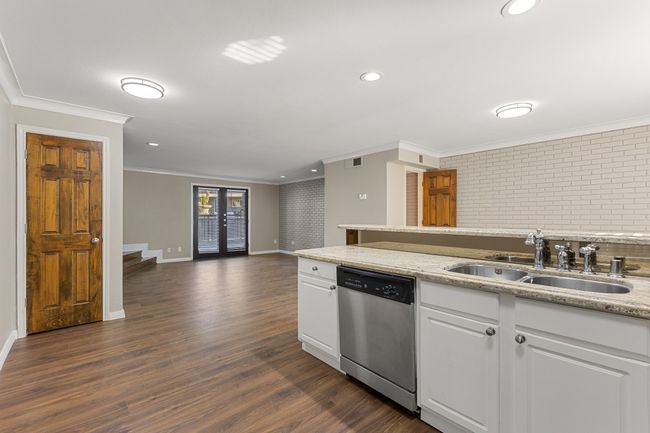 Kitchen featuring stainless steel dishwasher, a sink, ornamental molding, and baseboards | Image 8