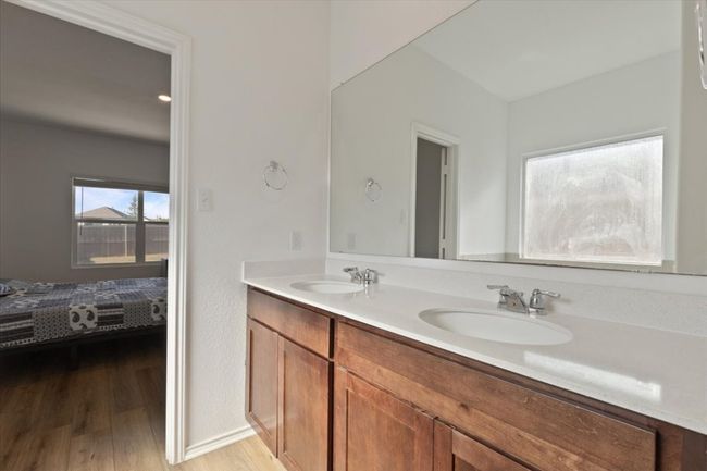 Ensuite bathroom featuring double vanity, connected bathroom, wood finished floors, and a sink | Image 10