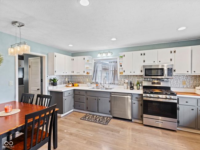 kitchen with open shelves, gray cabinets, stainless steel appliances, a sink, and light wood-style flooring | Image 9