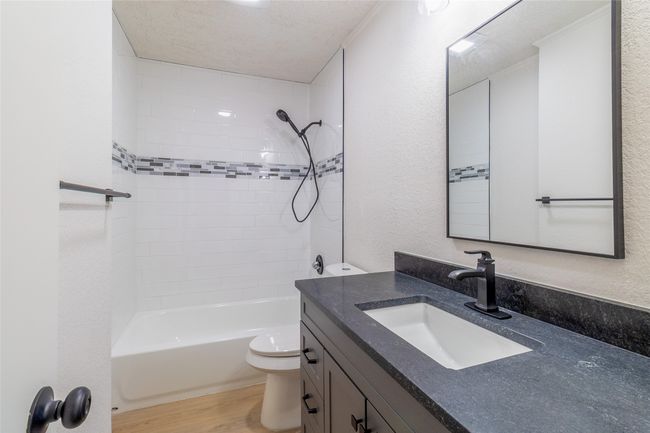 Full bathroom featuring toilet, shower / bathing tub combination, wood finished floors, a textured wall, and vanity | Image 19