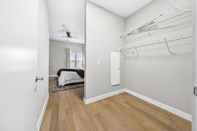 Walk in closet with ceiling fan and light wood finished floors | Image 19