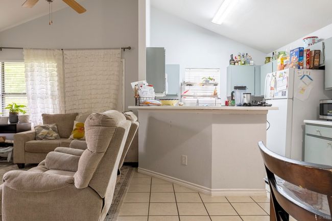 Kitchen with freestanding refrigerator, ceiling fan, light tile patterned floors, stainless steel microwave, and high vaulted ceiling | Image 12