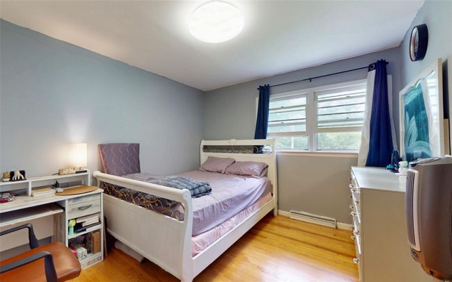 Bedroom with baseboard heating, light wood-type flooring, and baseboards | Image 35