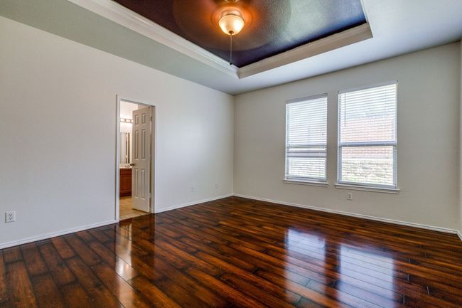 Empty room featuring crown molding, a tray ceiling, baseboards, and hardwood / wood-style flooring | Image 9