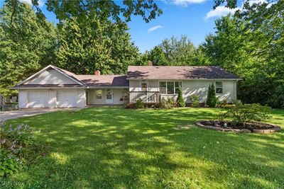 Ranch-style house featuring a wooden deck, a front lawn, and a garage | Image 3