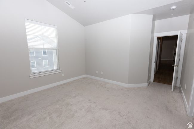Spare room featuring lofted ceiling, light colored carpet, and baseboards | Image 22