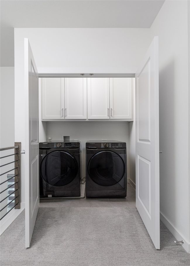Laundry room featuring cabinet space, washer and dryer, and light colored carpet | Image 24
