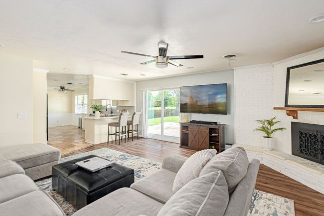 Living area with ceiling fan, a brick fireplace, and light wood finished floors | Image 28