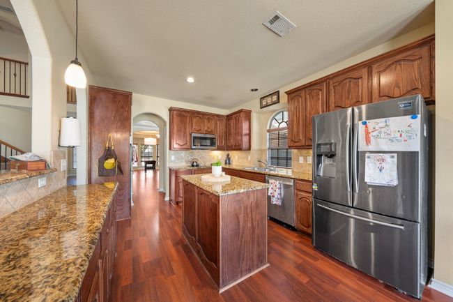 Kitchen featuring stainless steel appliances, arched walkways, visible vents, and dark wood-style floors | Image 8