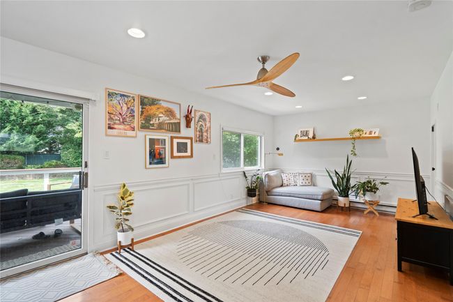 Living room with wood finished floors, a decorative wall, wainscoting, a ceiling fan, and recessed lighting | Image 9