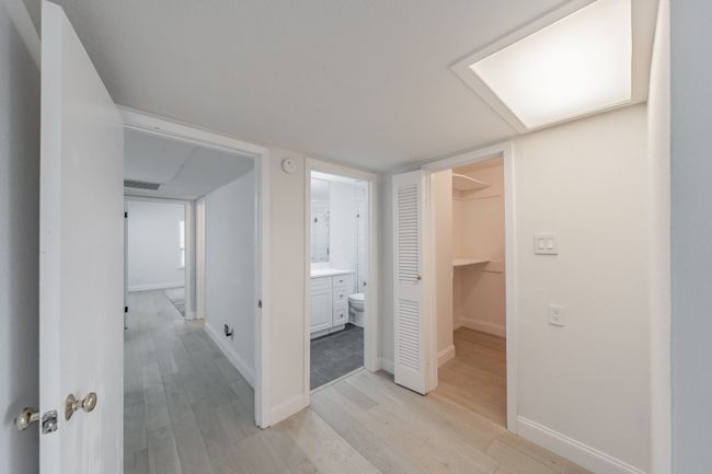 Hallway with visible vents, light wood finished floors, and baseboards | Image 12