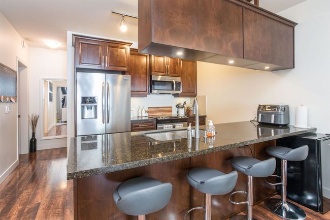 Kitchen with a breakfast bar, stainless steel appliances, dark wood finished floors, and a sink | Image 4