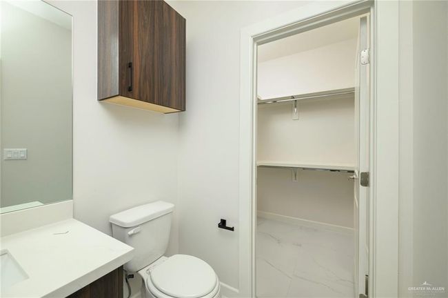 Bathroom with marble finish floors, toilet, vanity, baseboards, and a spacious closet | Image 14