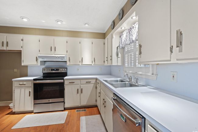 Kitchen featuring under cabinet range hood, stainless steel appliances, light countertops, visible vents, and a sink | Image 6