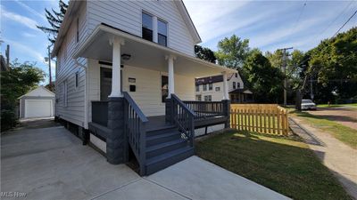 View of front of house featuring an outdoor structure, a garage, a porch, and a front lawn | Image 1