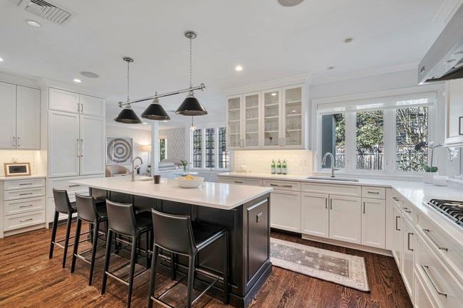 Kitchen featuring white cabinets, a breakfast bar/island and tons of natural light through the lead glass windows. | Image 5